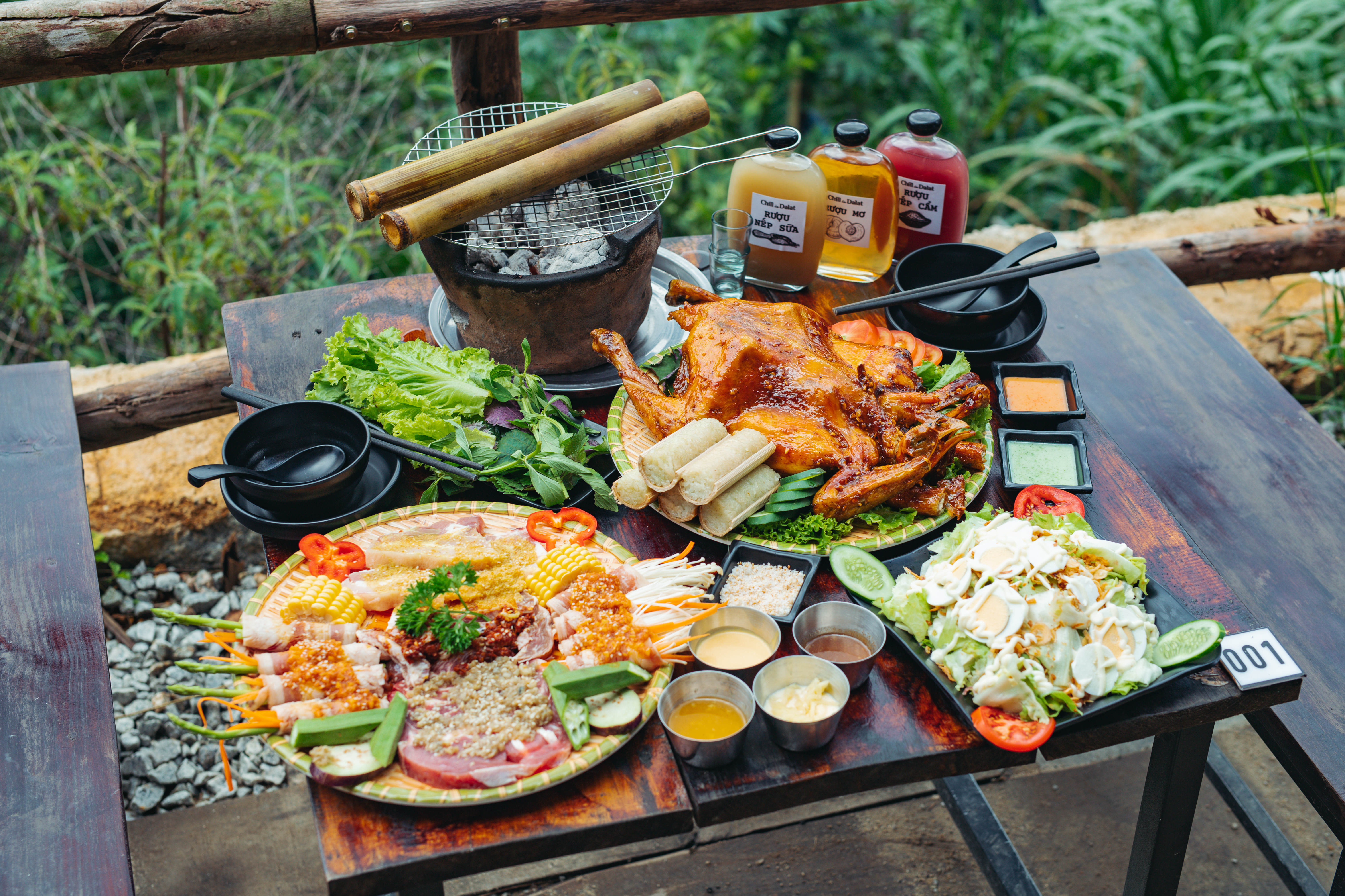 Bãi cỏ trước quán với bếp than hoa nướng gà đặt giữa sân